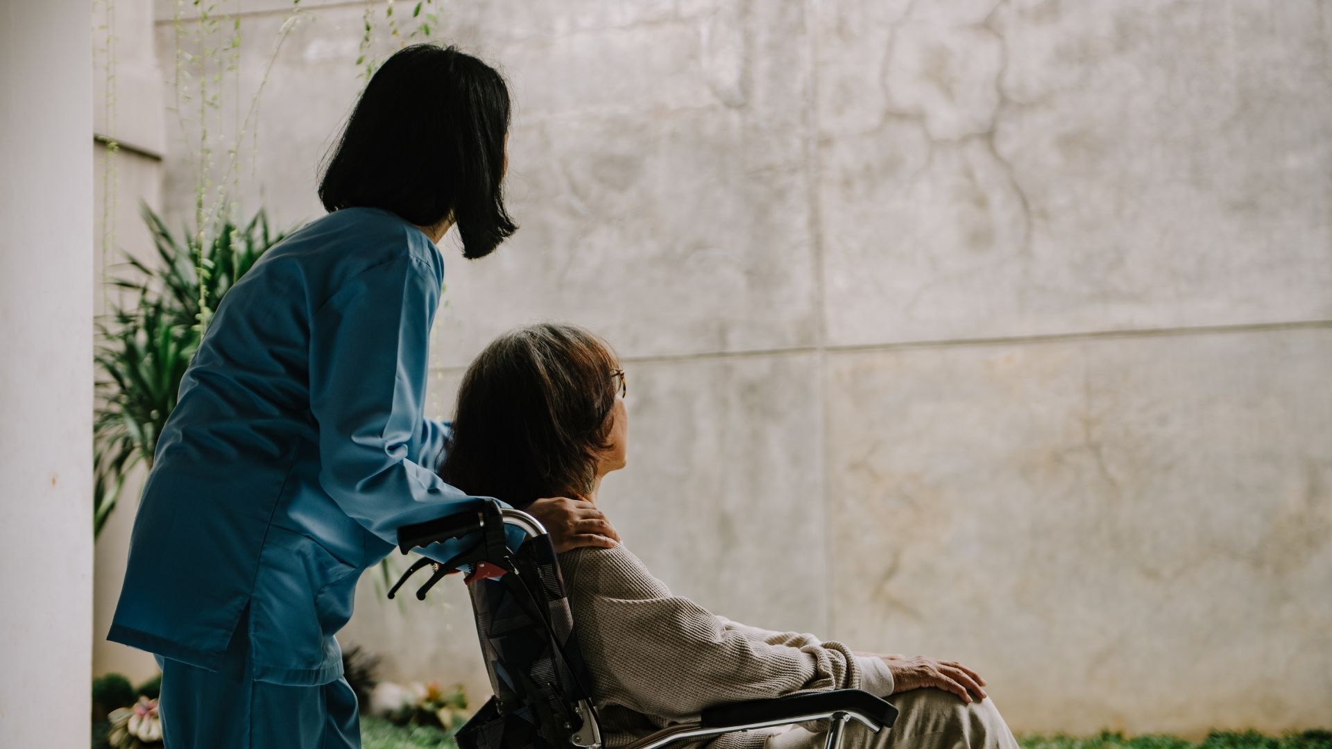 A woman is sitting on a couch talking to an older woman who is holding a piece of paper.