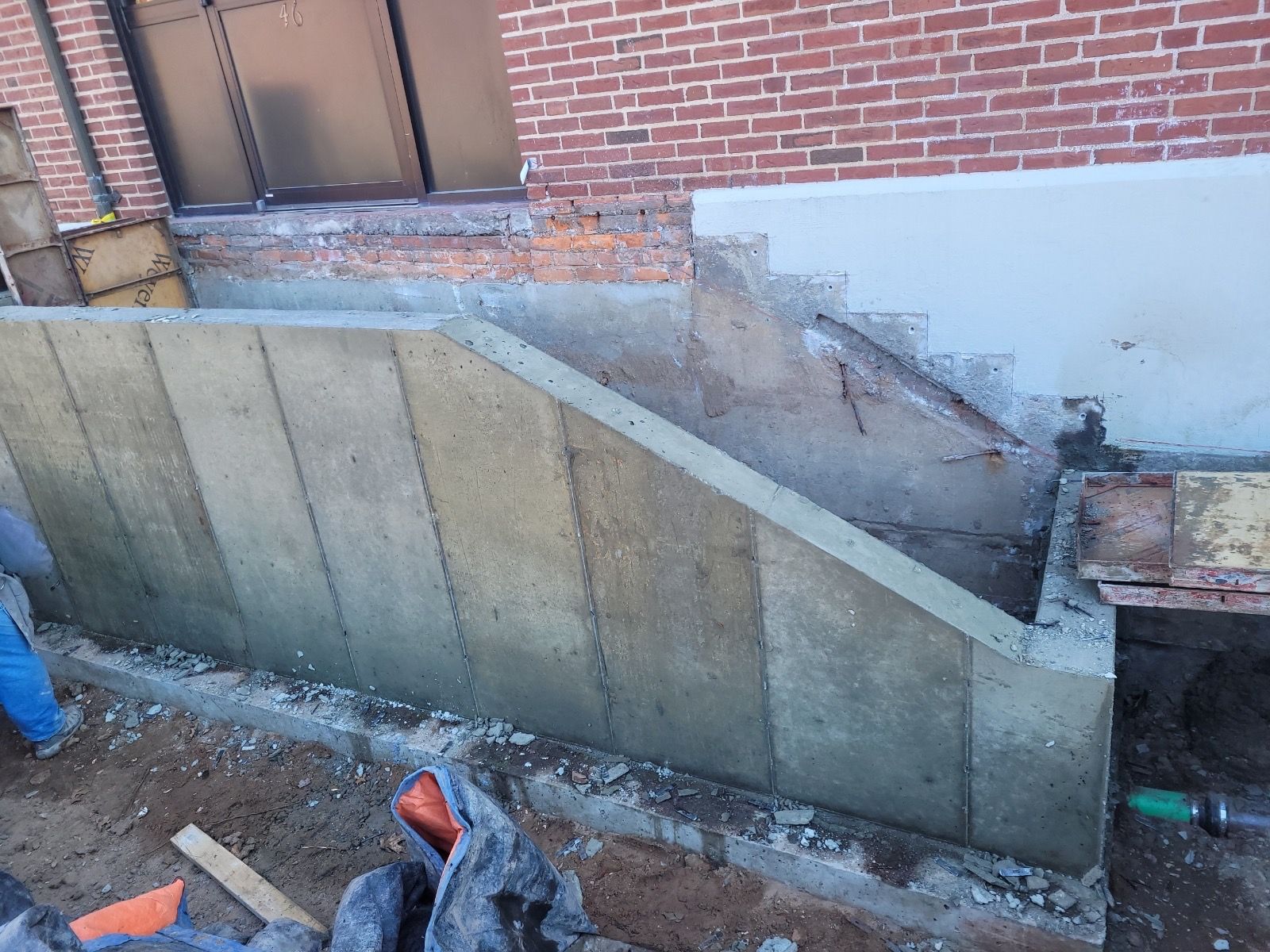 A concrete wall is being built next to a brick building.