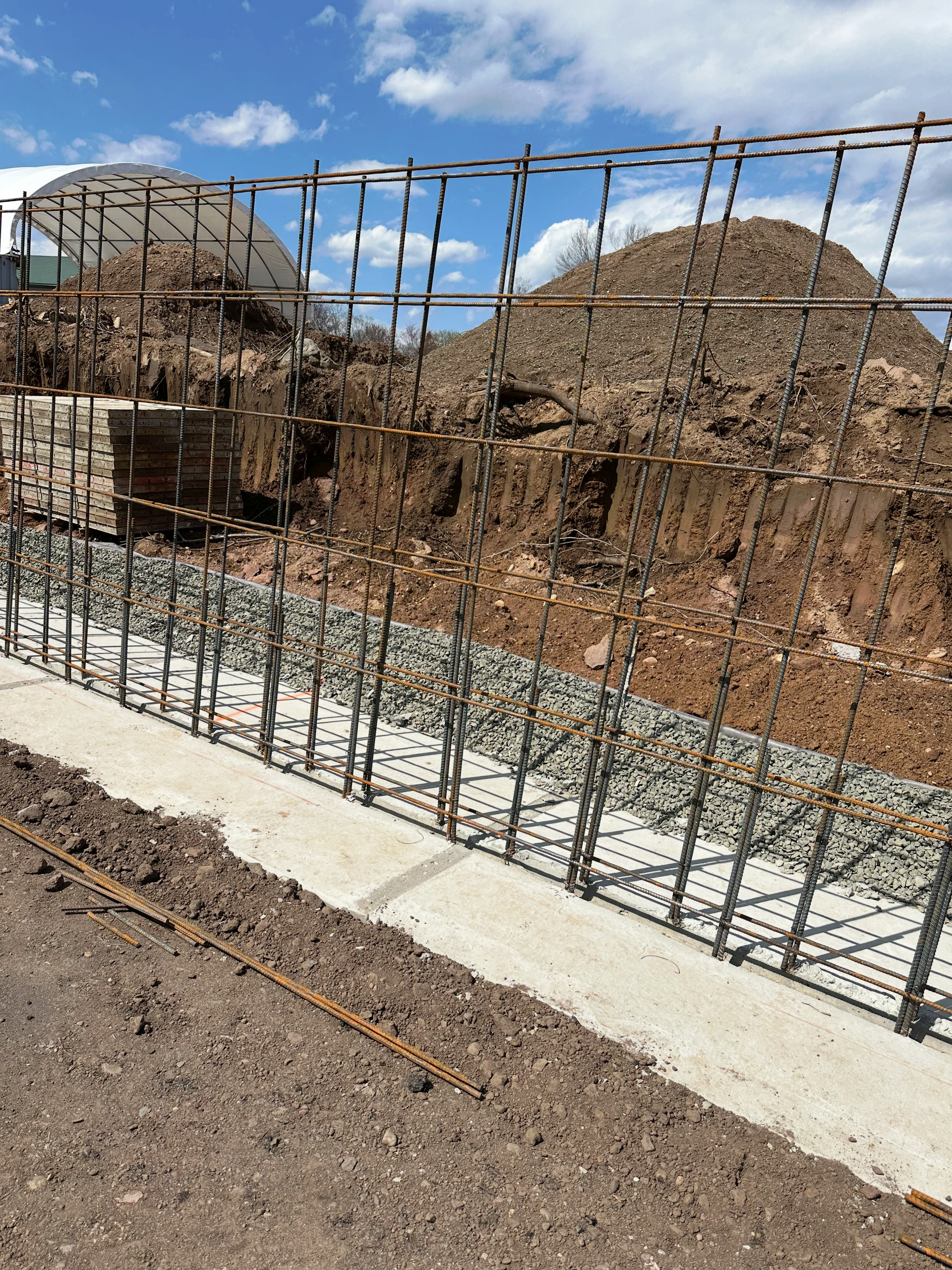 A large pile of dirt is behind a metal fence.