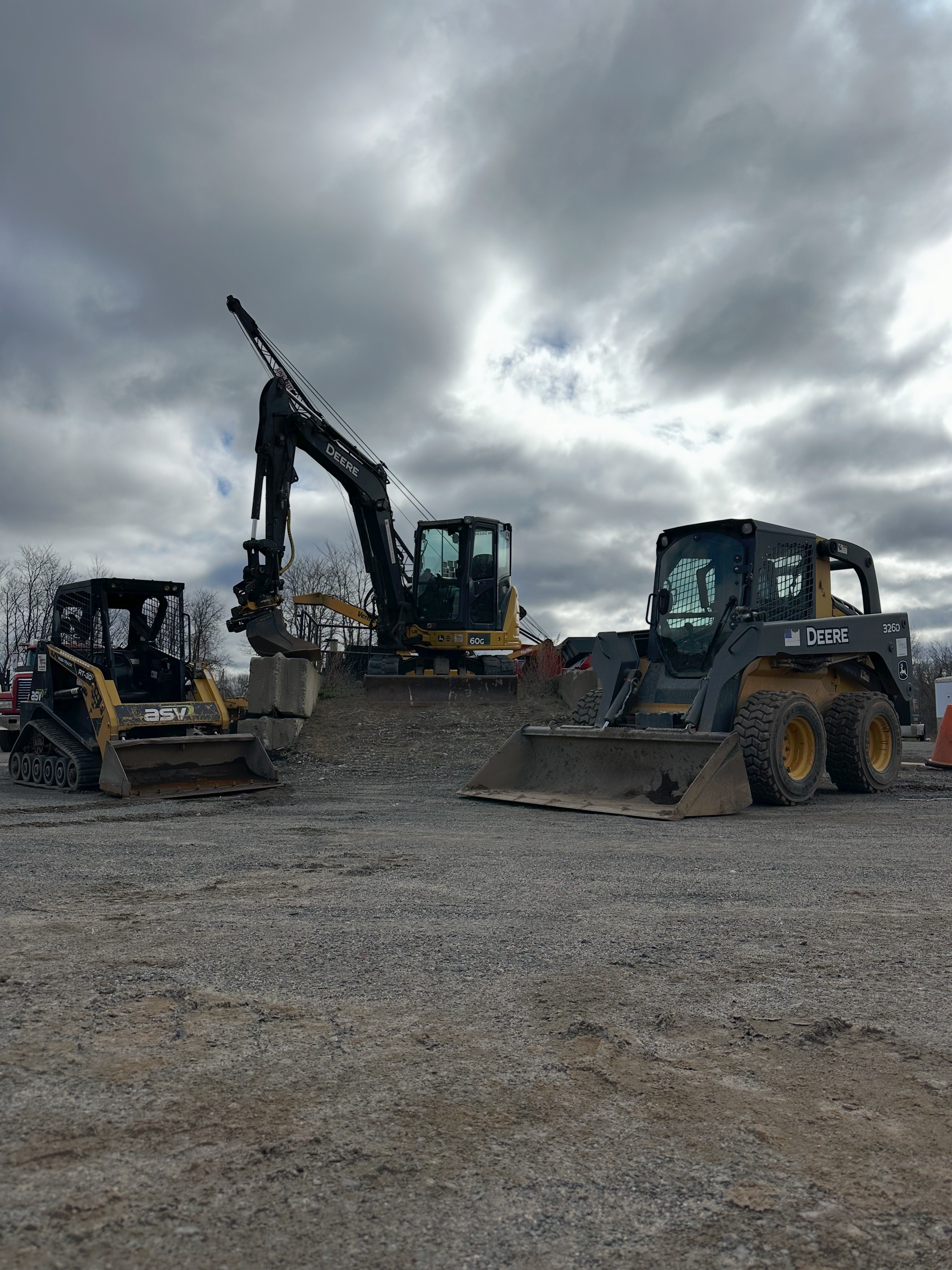 Two construction vehicles are parked in a gravel lot.