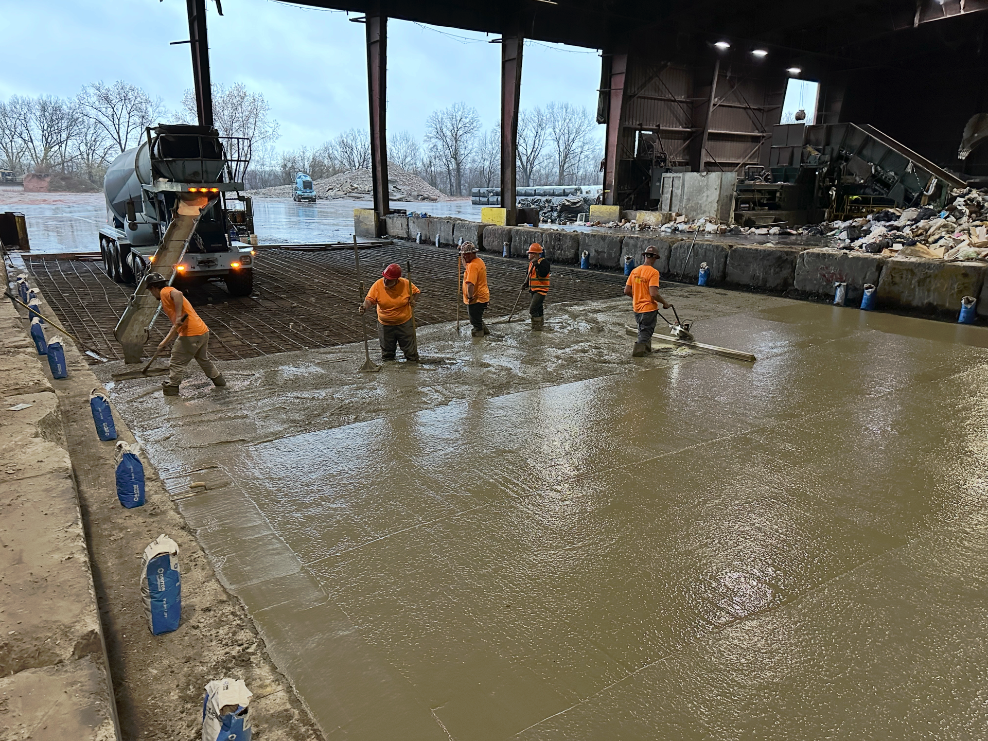 A group of construction workers are working on a concrete floor.