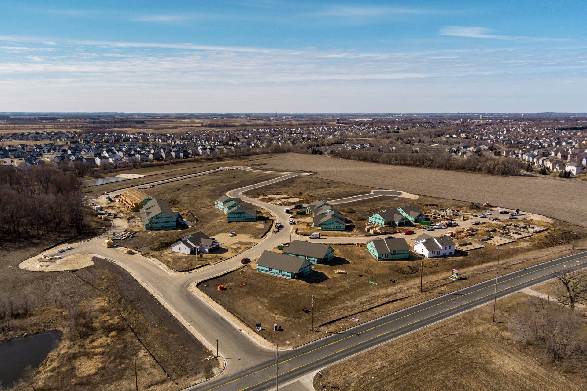 Aerial view of a suburban housing development with newly built turquoise houses on a sunny day.