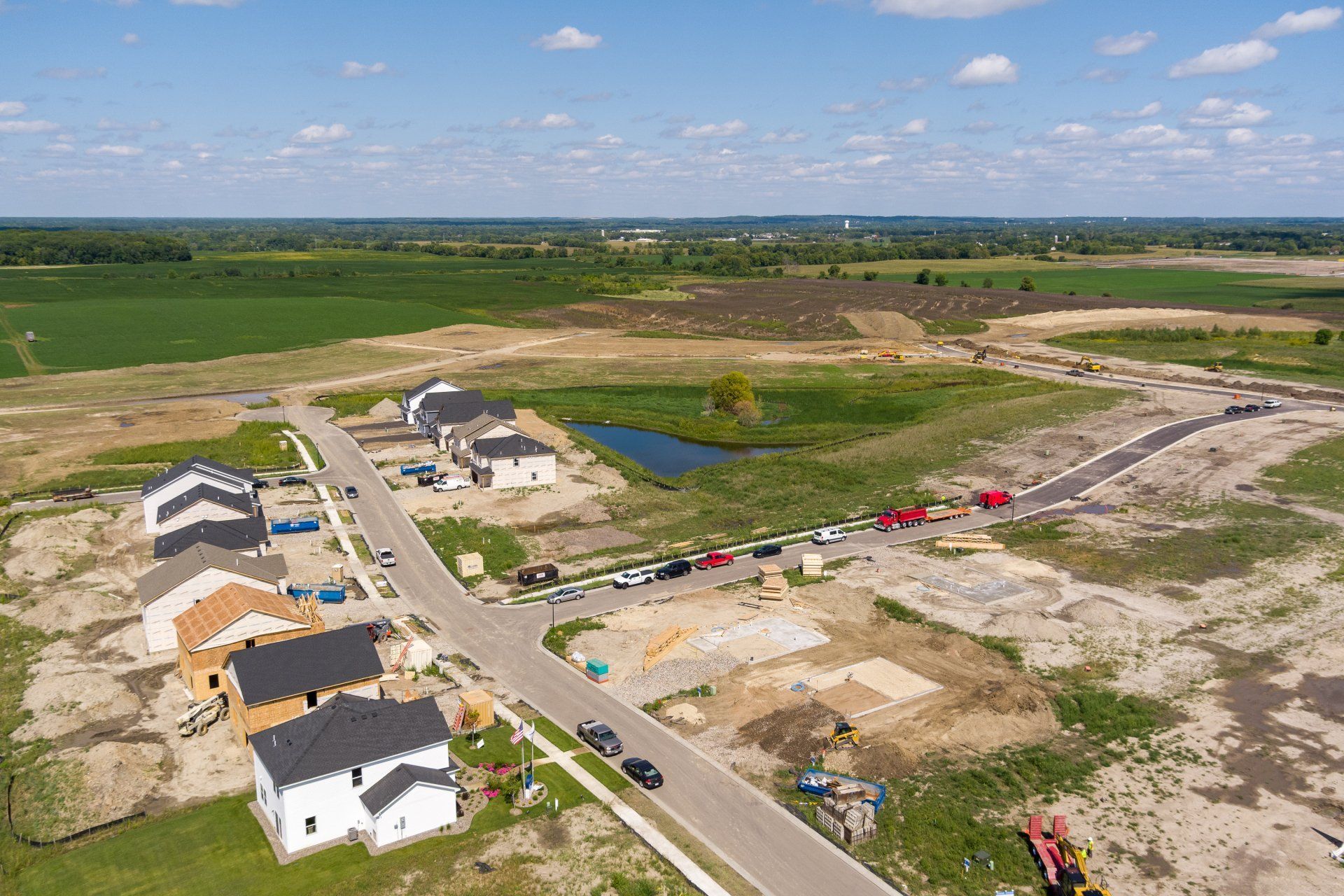 Aerial view of a new housing development under construction with homes, roads, and surrounding farmland.