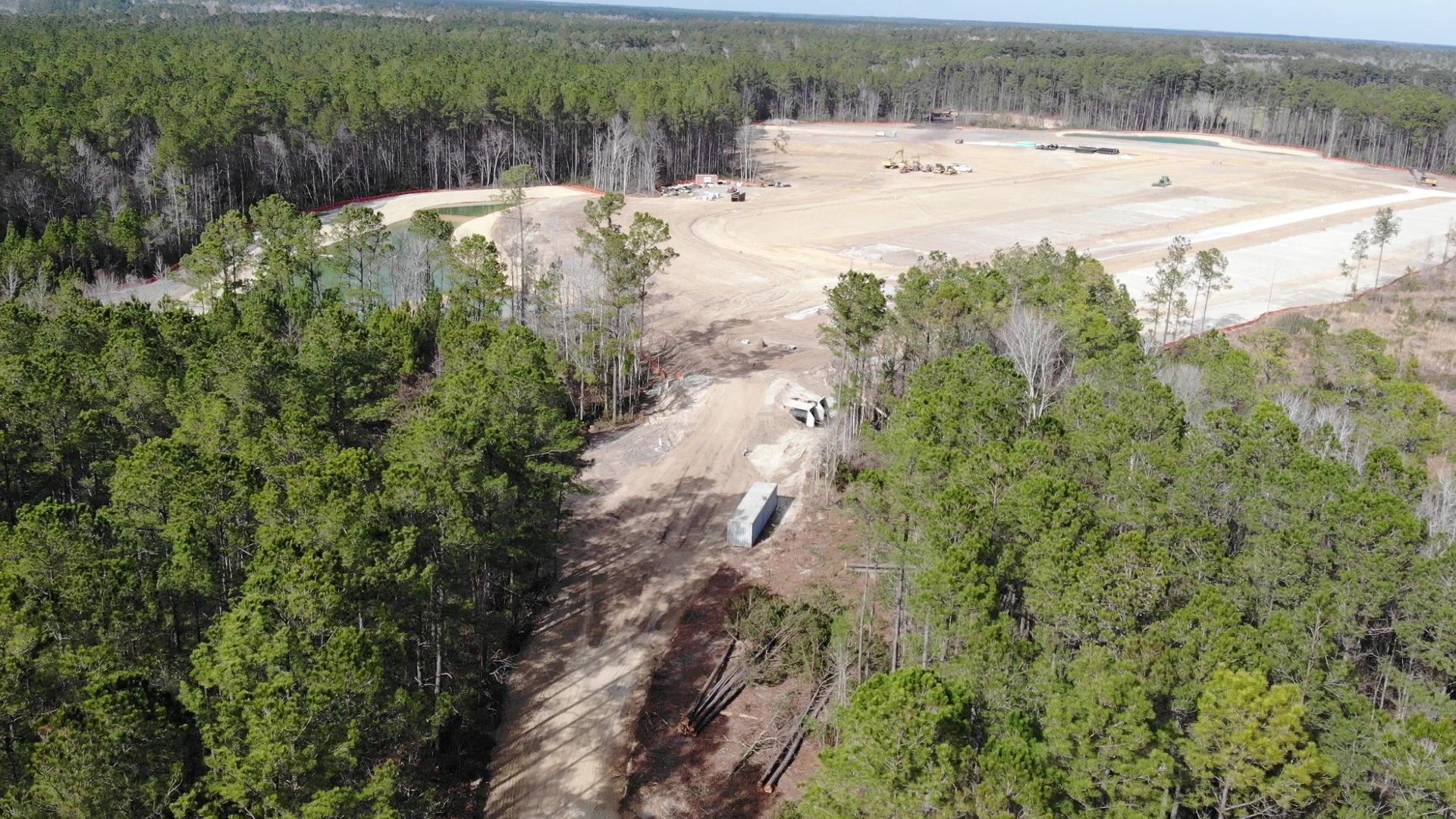 Aerial view of a clearing in a forest, showing construction with heavy machinery in a large dirt area.