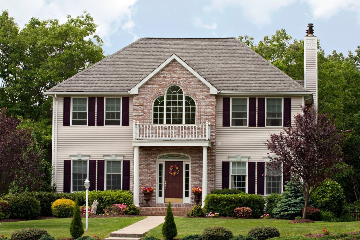 A large house with a brick facade and purple shutters on the windows.