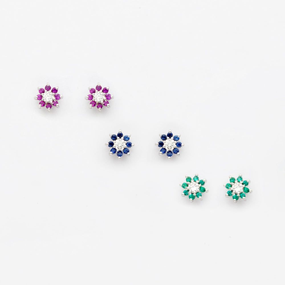 Un paio di orecchini con pietre di diversi colori su una superficie bianca.