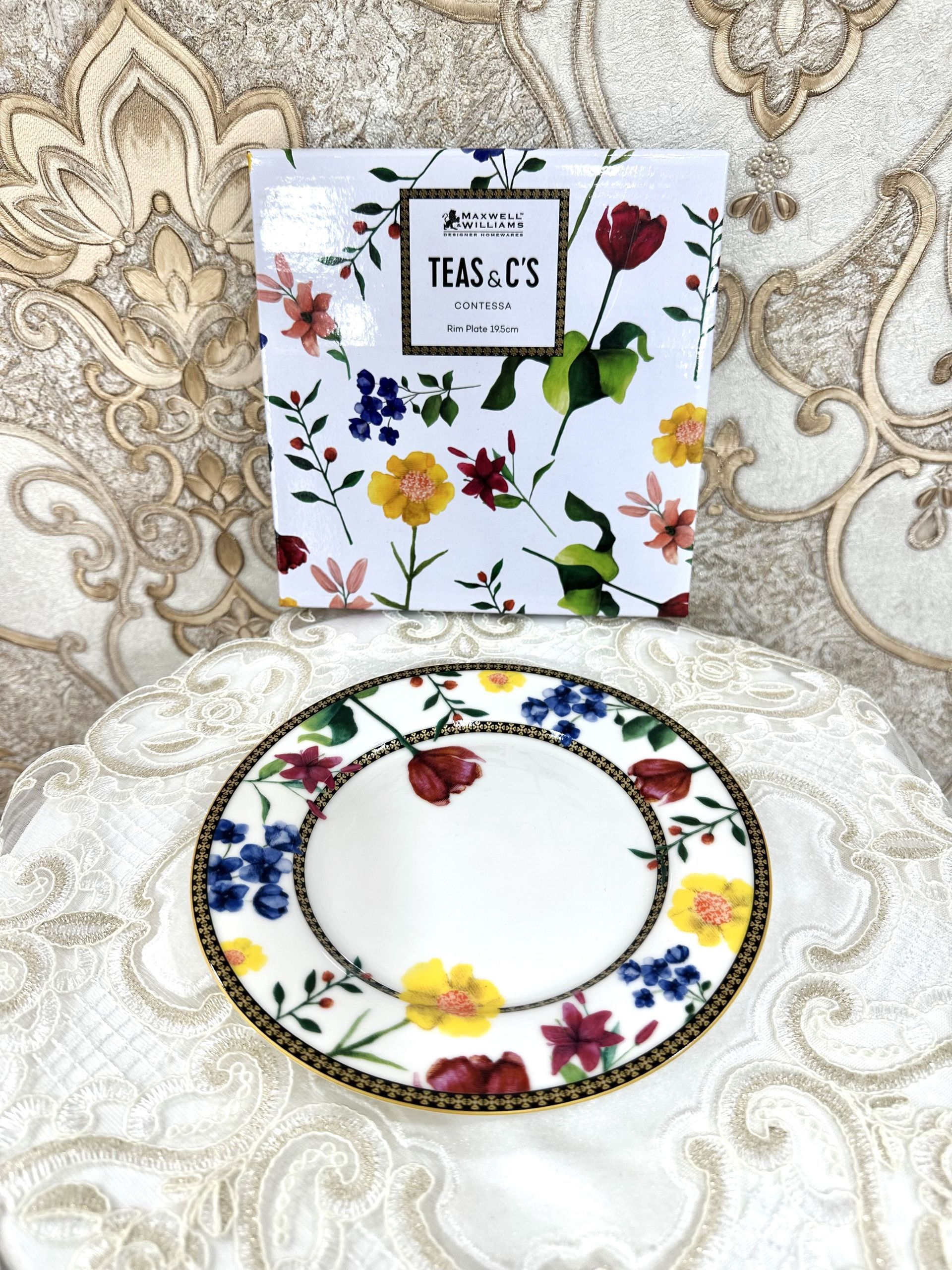 Un piatto con dei fiori sopra è appoggiato su un tavolo accanto a una scatola con la scritta