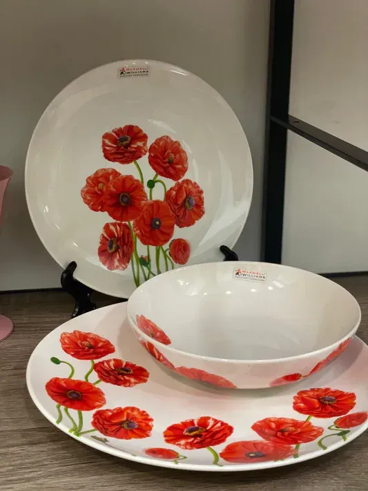 Tre piatti e una ciotola con sopra dei fiori rossi