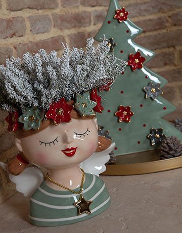 Un vaso con dei fiori è appoggiato accanto all'albero di Natale.