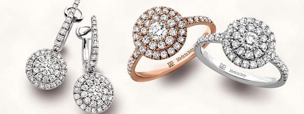 Un anello e degli orecchini sono appoggiati uno accanto all'altro su una superficie bianca.