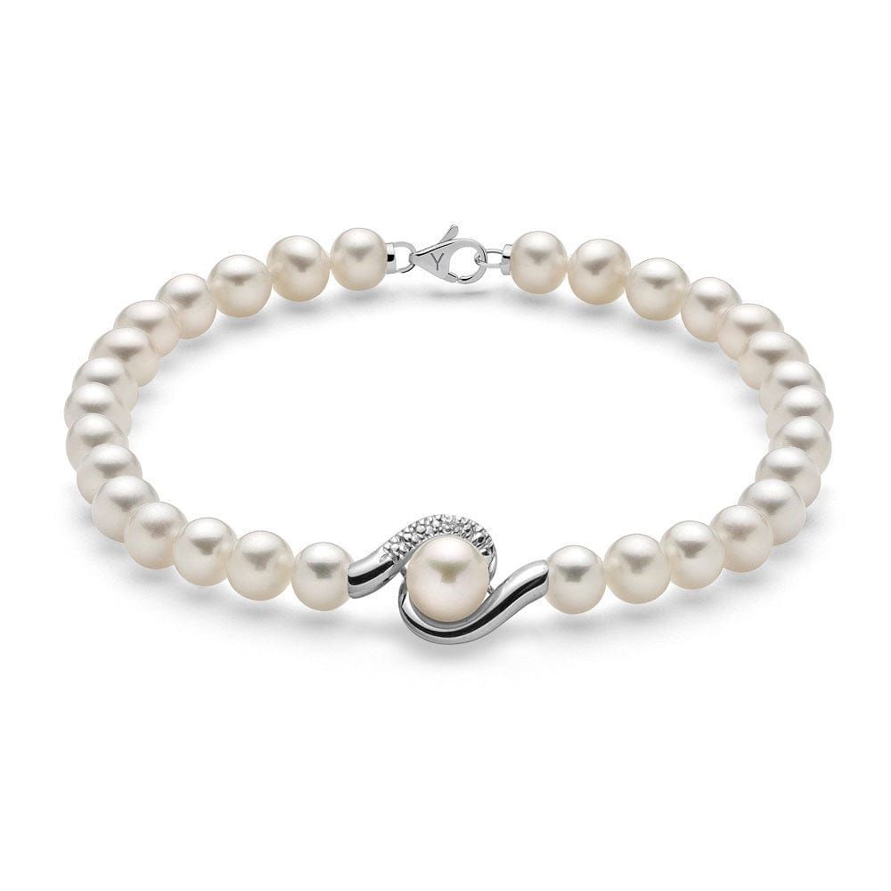 Un braccialetto fatto di perle bianche e diamanti su uno sfondo bianco.