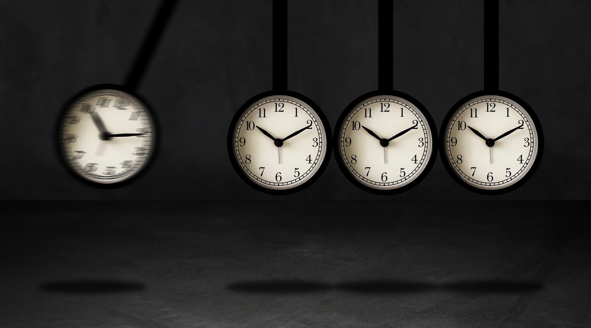 A row of clocks hanging from a string and one of them shows the time as 4:20
