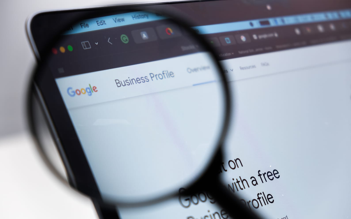 Magnifying glass over a laptop screen displaying the Google Business Profile webpage.