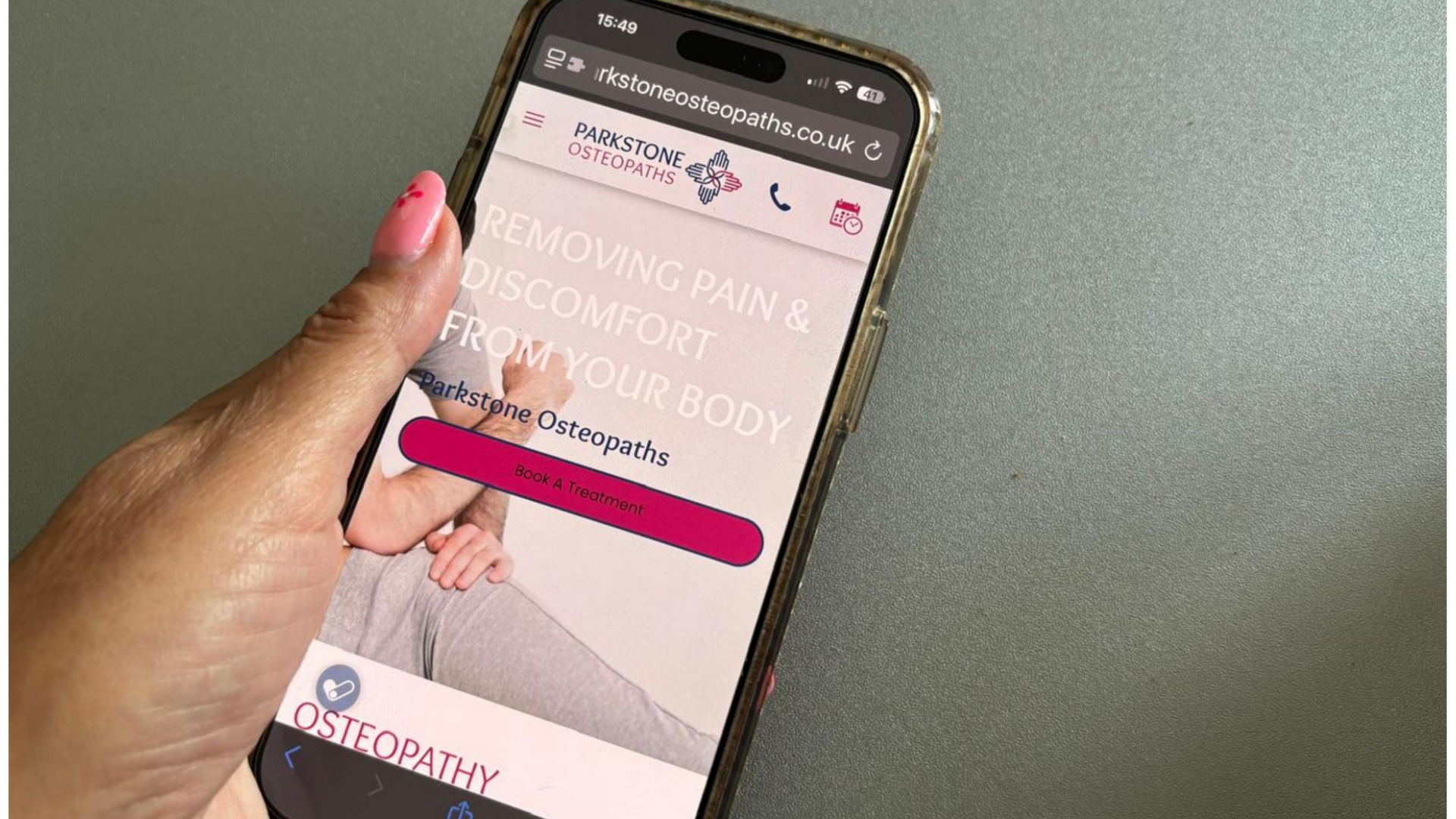 Person holding a phone displaying a website for osteopathy services.