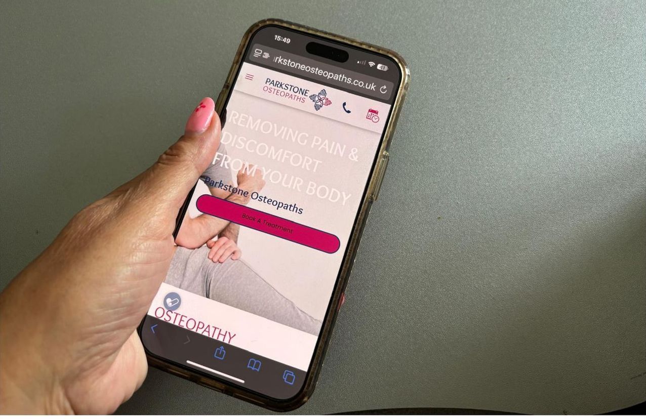 A person is holding a mobile phone with a website on it.
