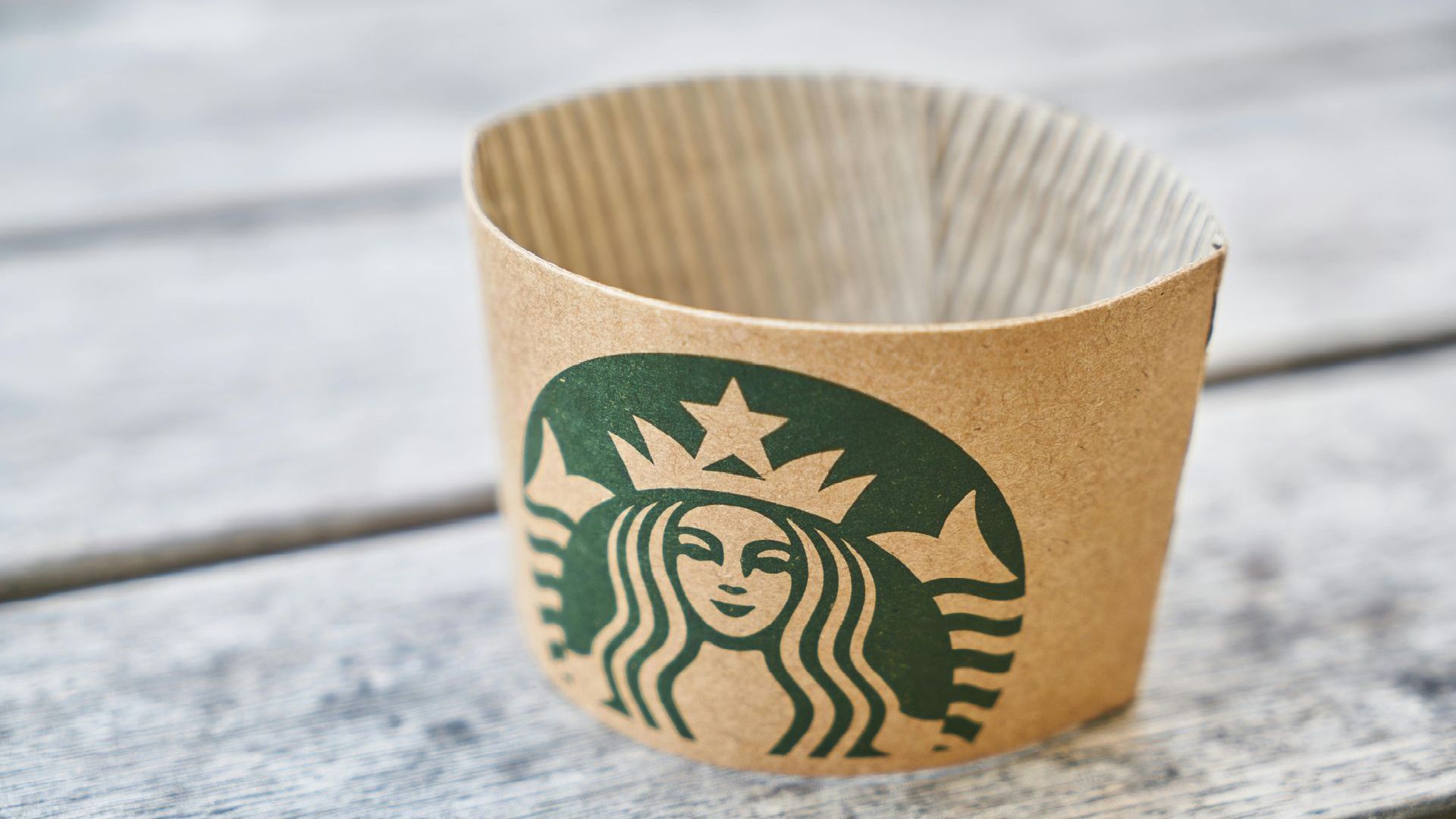 A starbucks cup is sitting on a wooden table.