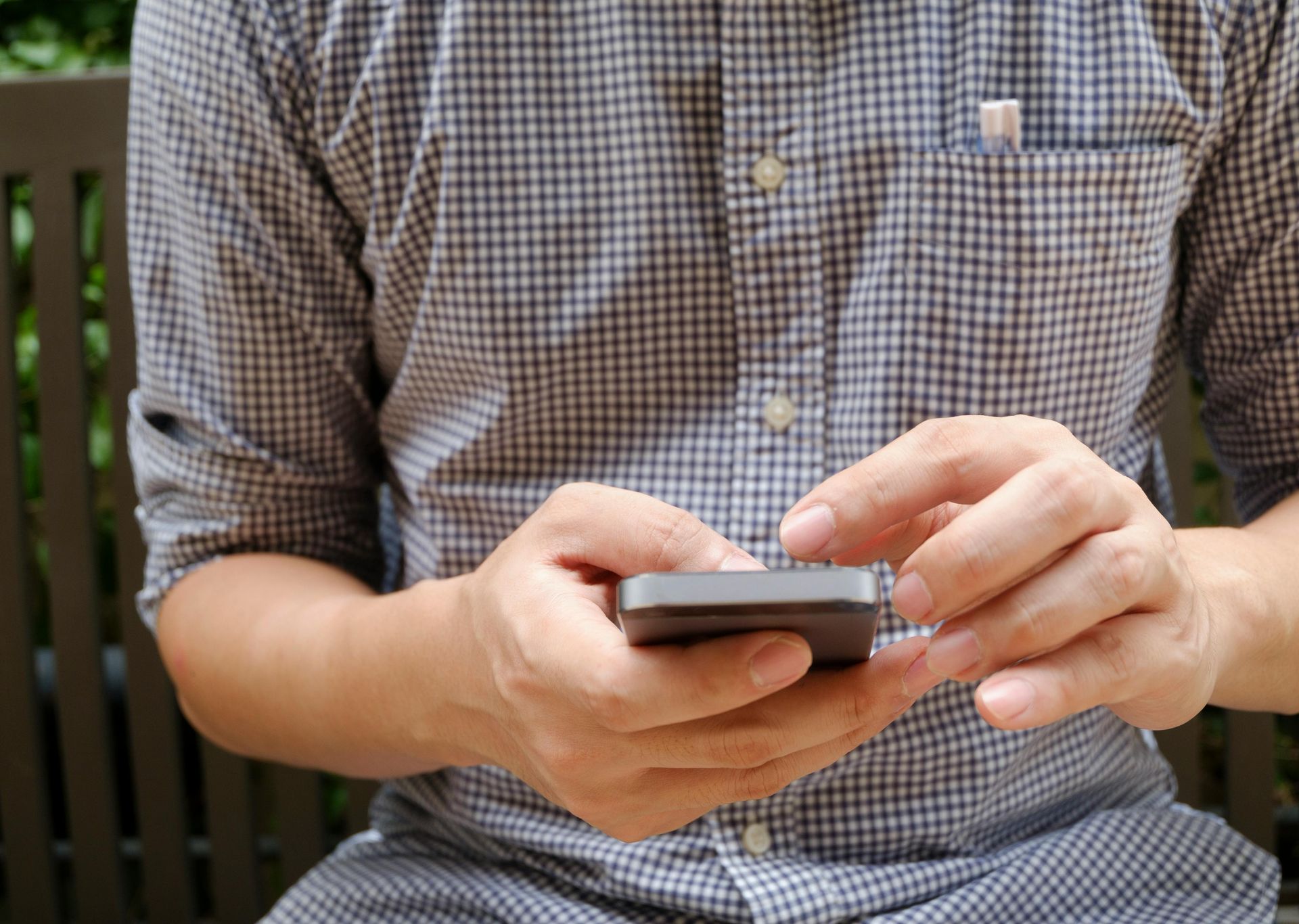 A man is sitting on a bench using a mobile phone.