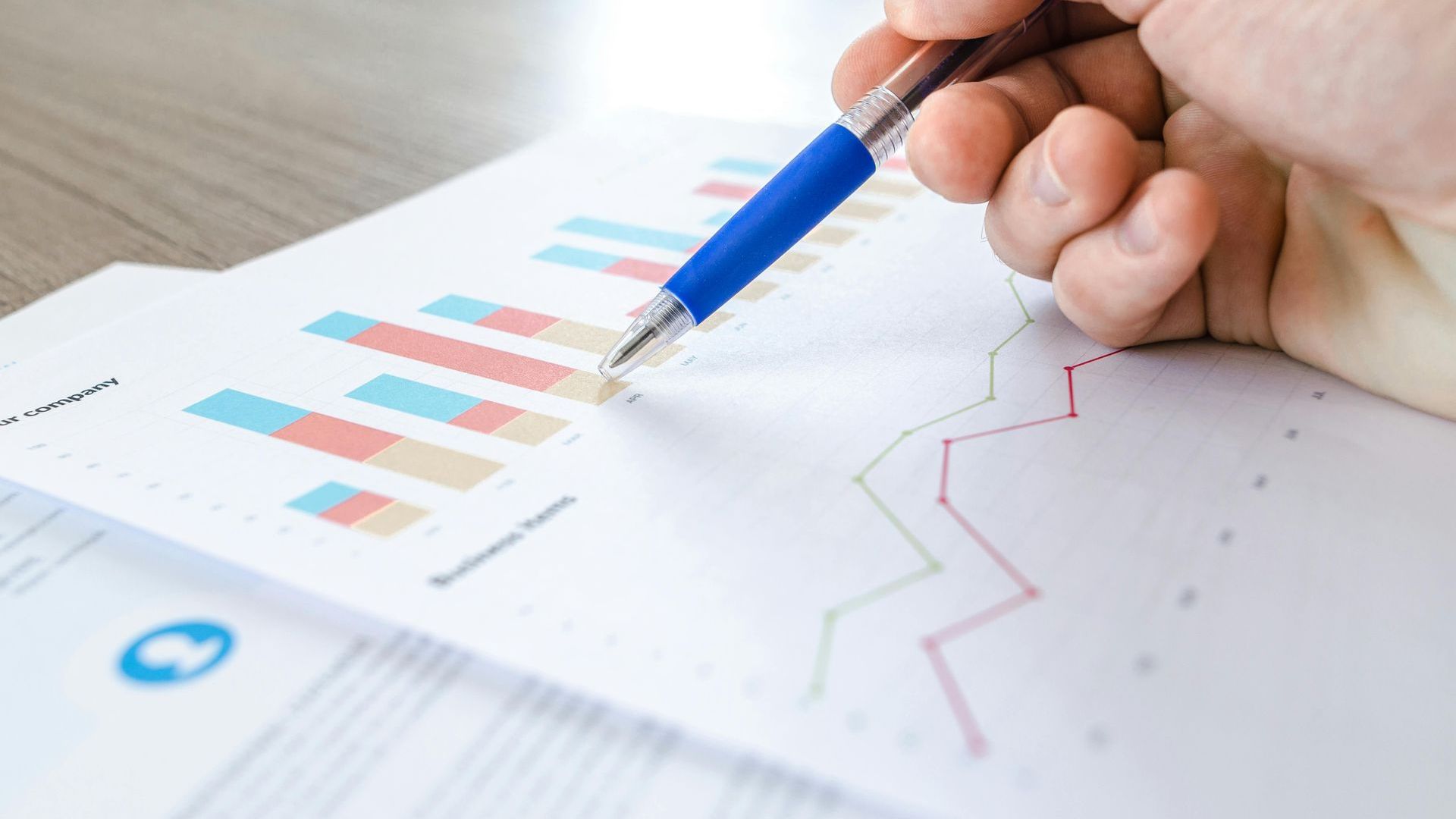 A person is holding a pen over a graph on a piece of paper.