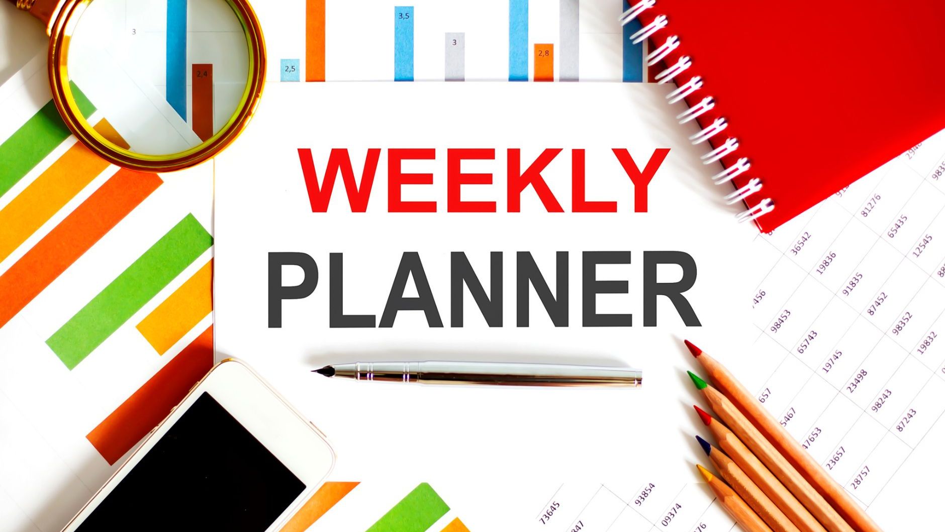 A weekly planner is sitting on a desk next to a cell phone , pencils , and a magnifying glass.