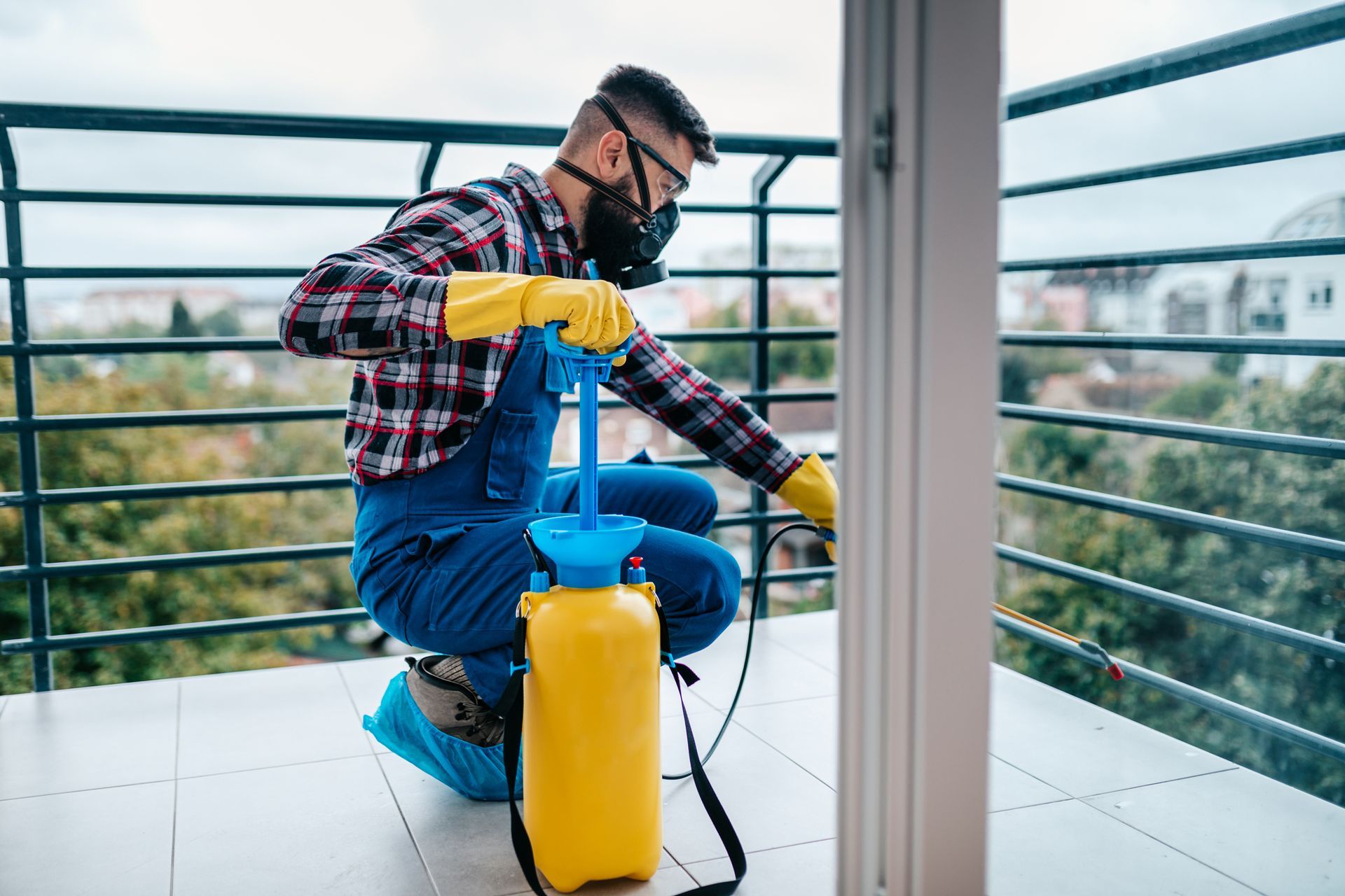 Exterminator in protective workwear spraying pesticide, showcasing expert pest control services.