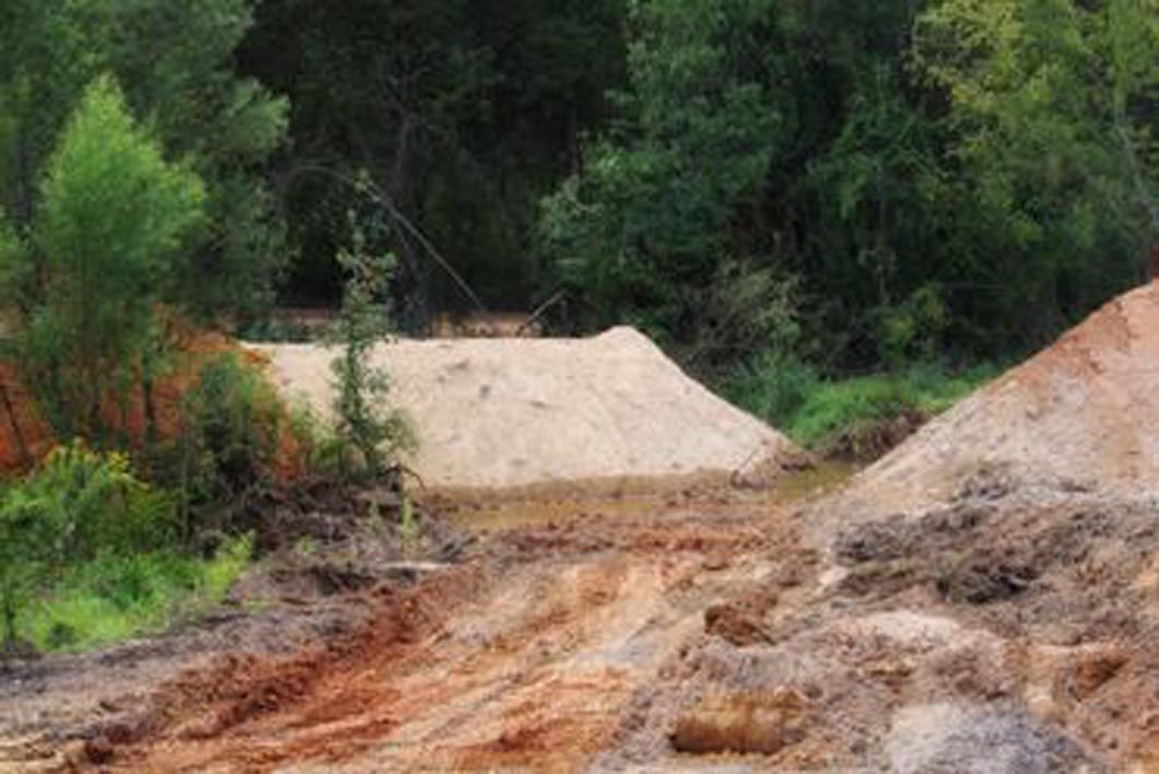A large pile of dirt is sitting in the middle of a forest.