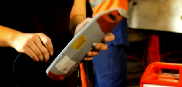 Person holding a device with a cable, likely for testing or measurement, possibly in a work environment. Person holding a device with a cable, likely for testing or measurement, possibly in a work environment.