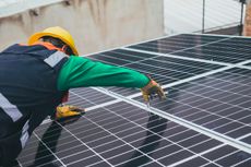 A man is working on a solar panel on the roof of a building.