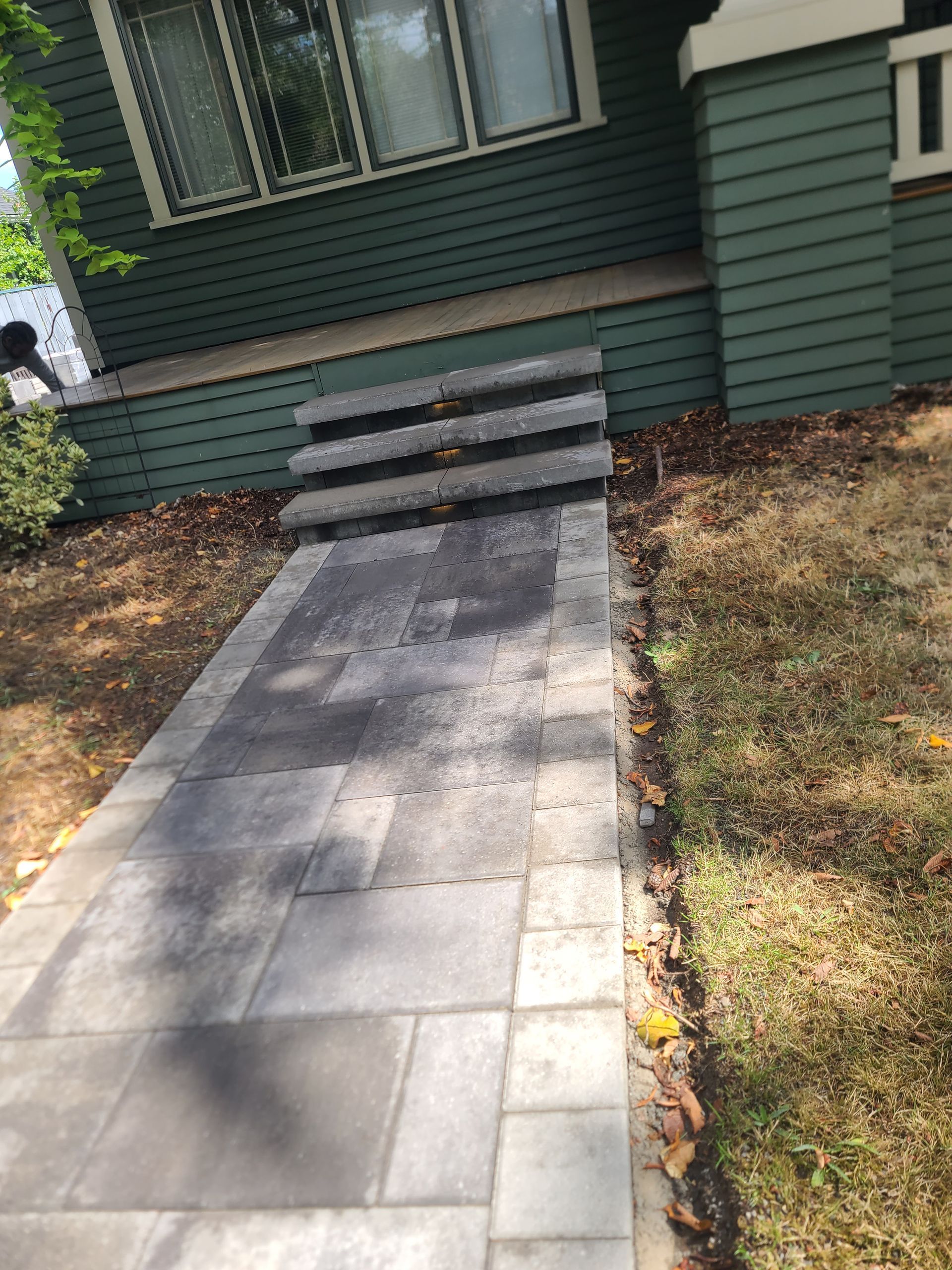 A walkway with stairs leading up to a green house.