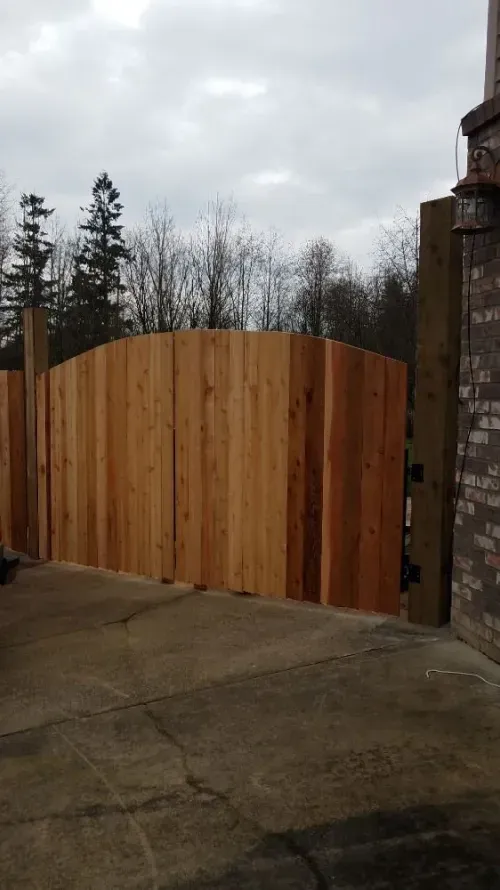 A wooden fence is sitting in a driveway next to a brick building.