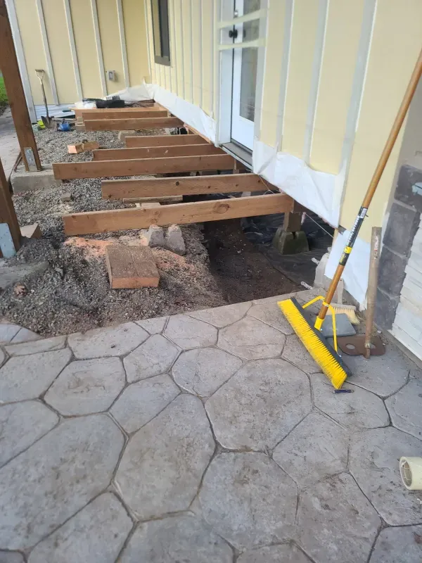 A yellow broom is sitting on a patio next to a house