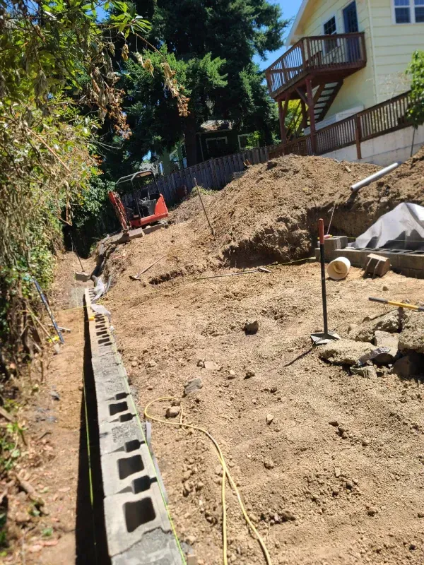 A house is being built on a hill with a large pile of dirt in front of it.