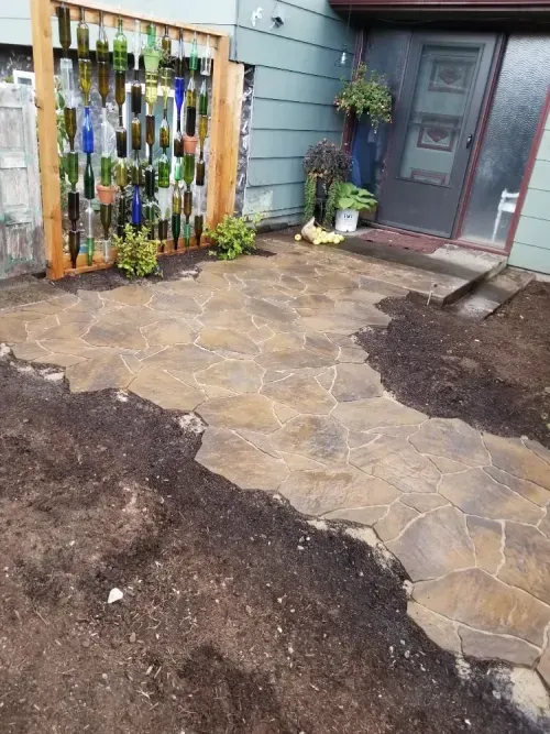 A stone walkway is being built in front of a house.