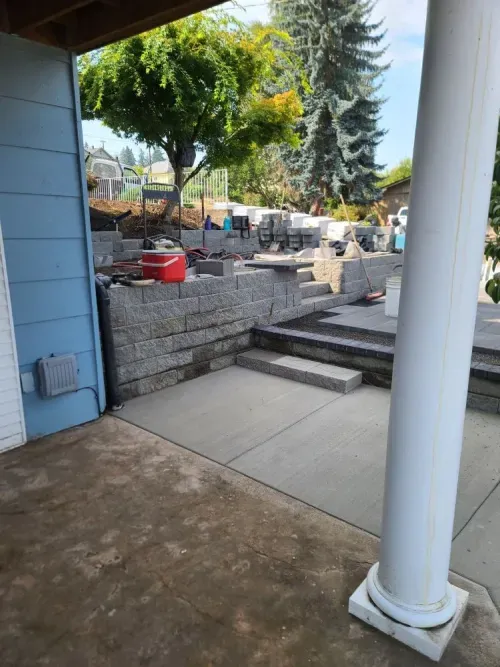 A patio area with a brick wall and steps being built in front of a house.