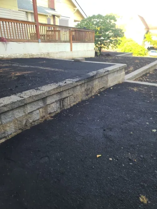 A black asphalt driveway with a stone wall in the background