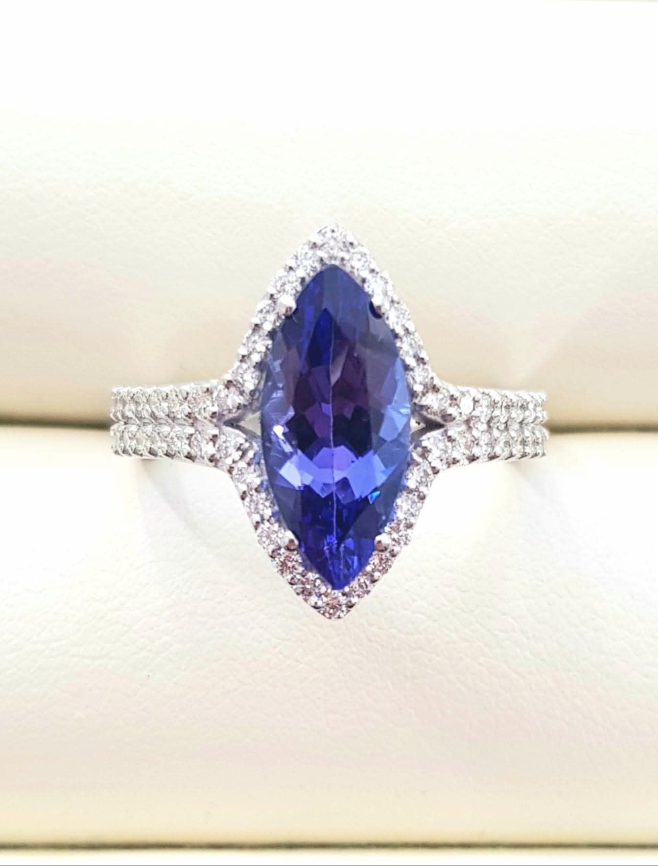 Anello con pietra preziosa viola taglio marquise, alone di diamanti e fascia tempestata di diamanti.
