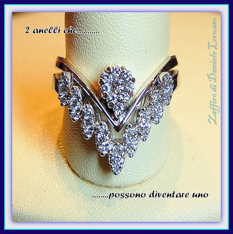 Due anelli di diamanti, uno a forma di V, su un supporto bianco. La scritta dice