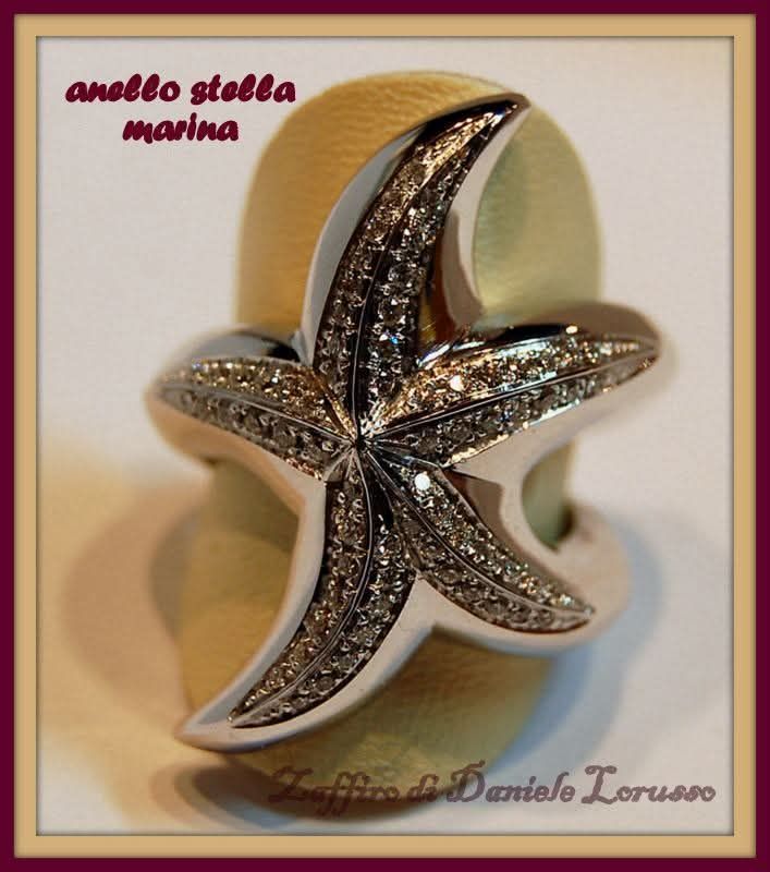 Anello a forma di stella marina tempestato di diamanti su un espositore. Sopra è scritto