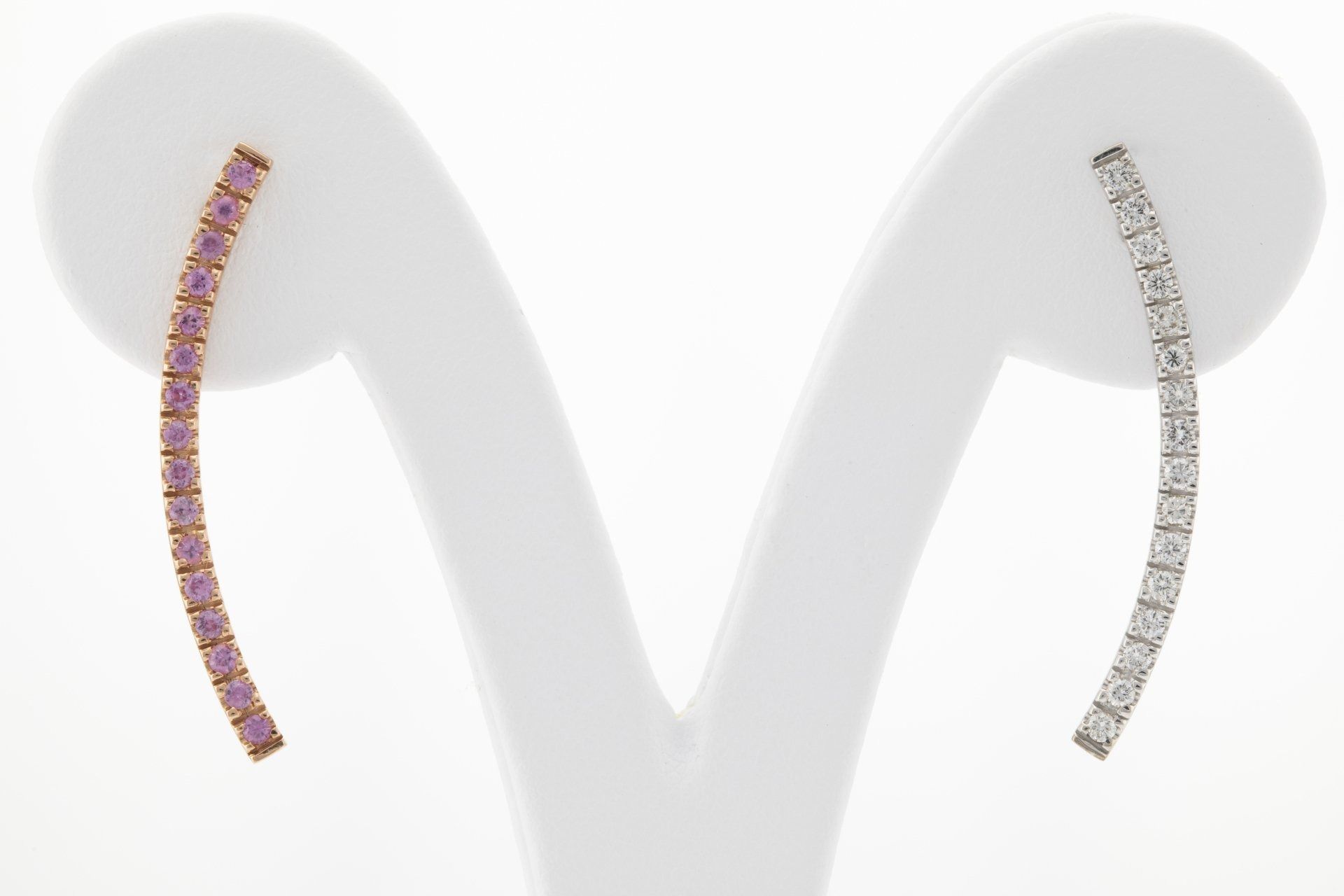 Orecchini: linee curve, pietre rosa (sinistra) e pietre trasparenti (destra), esposti su supporti bianchi.