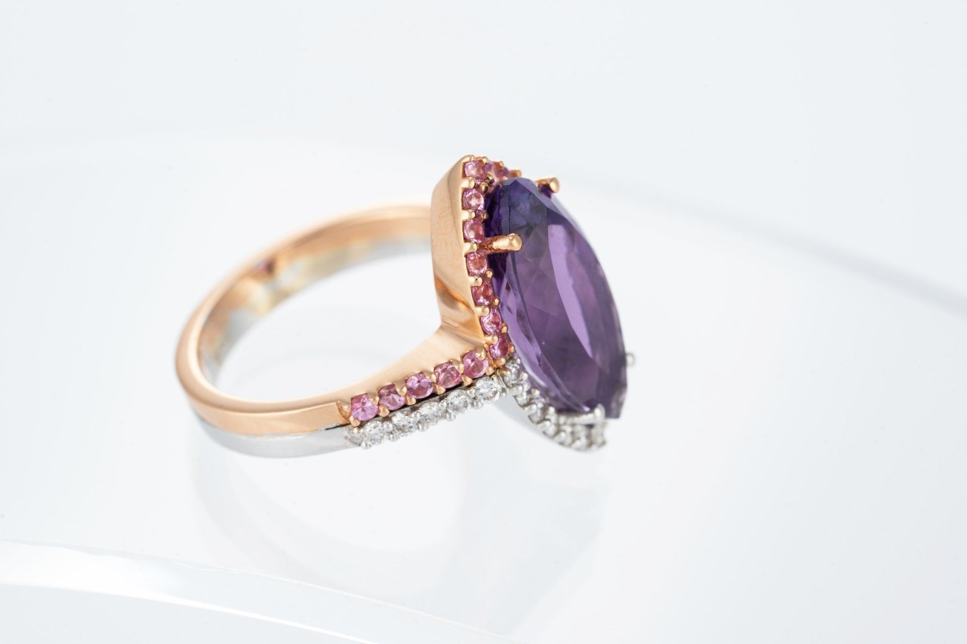 Anello in oro rosa con una grande pietra preziosa viola e dettagli rosa e bianchi.