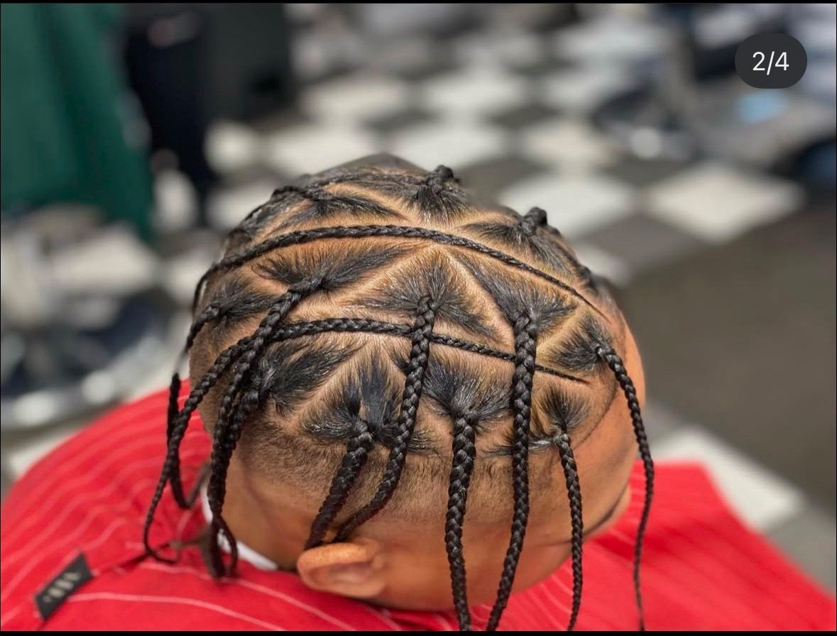 A man with braids in his hair is wearing a red shirt.