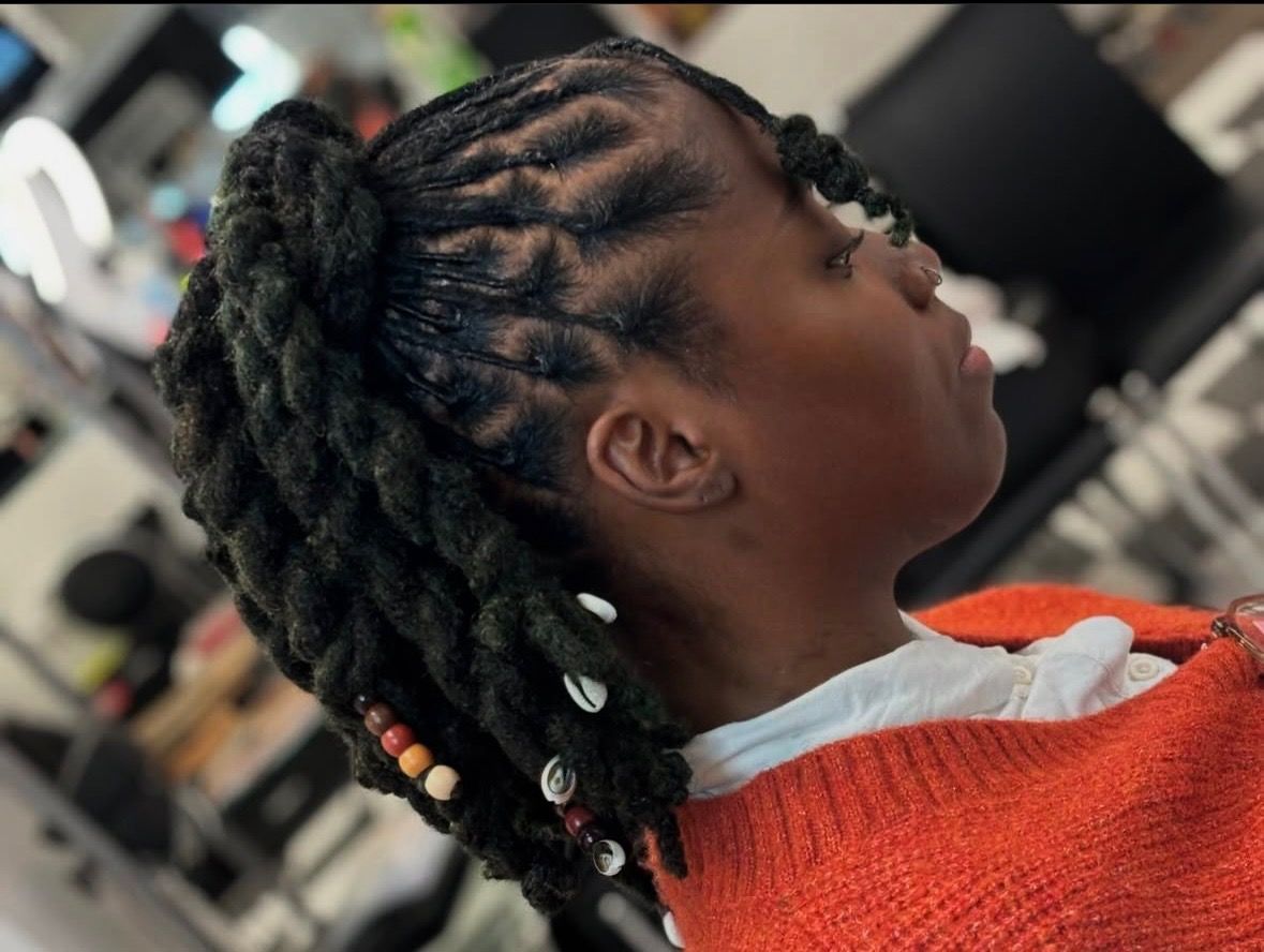 A woman with dreadlocks is wearing an orange sweater.