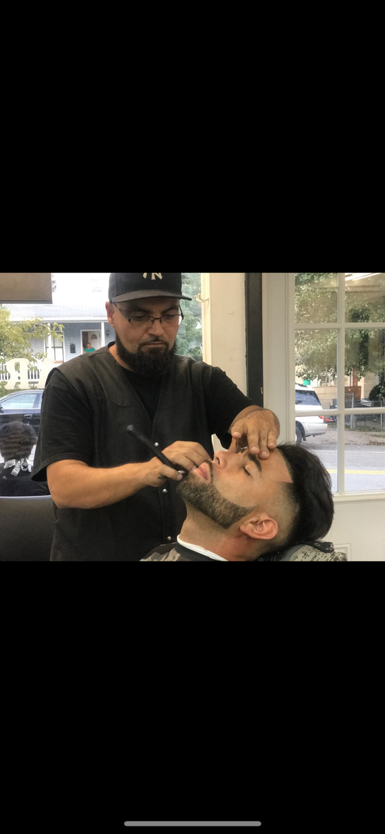 A man is getting his beard shaved by a barber in a barber shop.