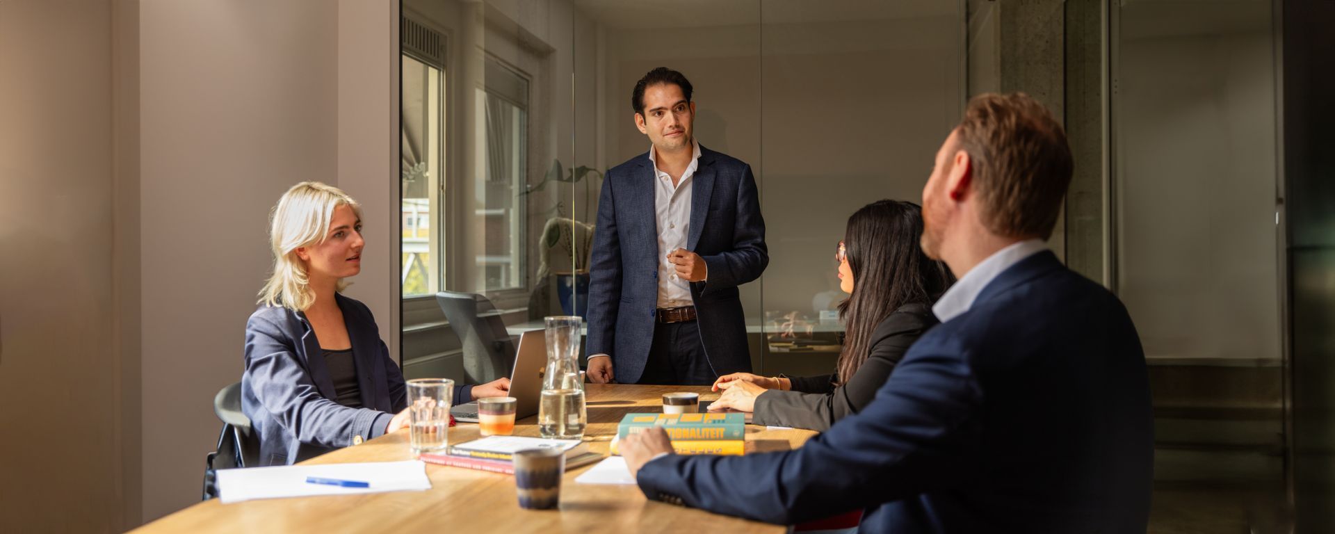Een groep mensen zit aan een tafel en bespreekt ideeën, waarbij overtuigingsstrategieën worden toegepast.