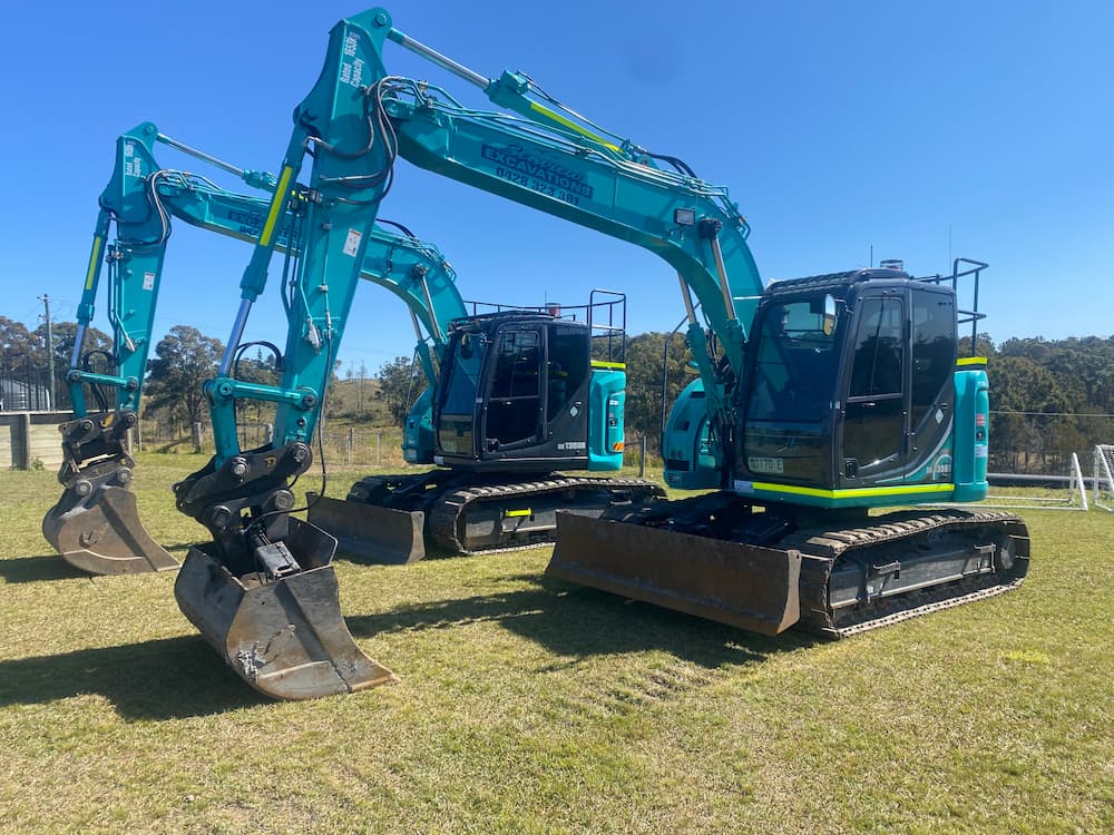 Two Blue Excavator in Field — Seaview Excavations in Hallidays Point, NSW