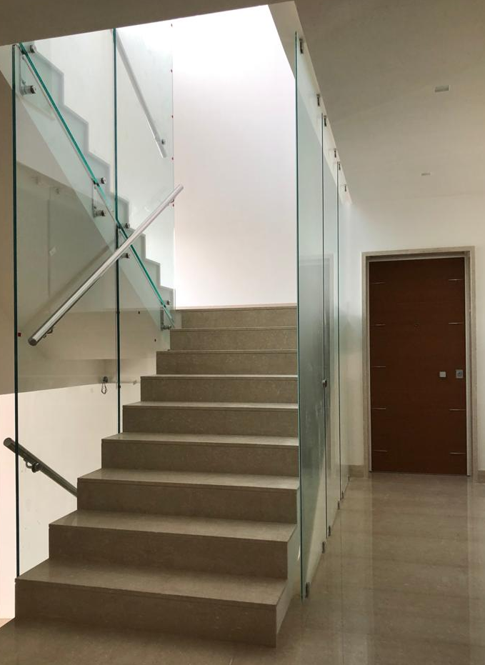 Una rampa di scale con ringhiera in vetro e una porta