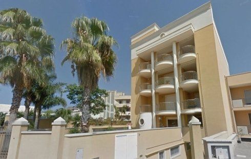 Un grande edificio con balconi e palme davanti