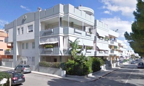 Un grande condominio con le auto parcheggiate di fronte