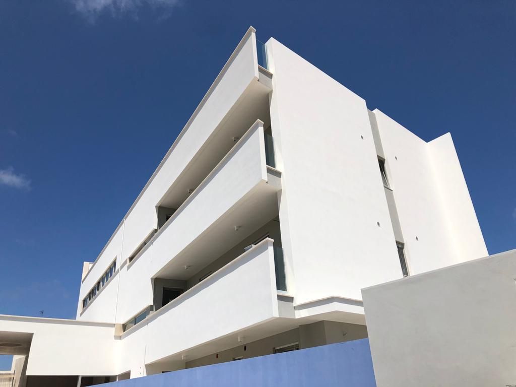 Un grande edificio bianco con balconi contro un cielo azzurro