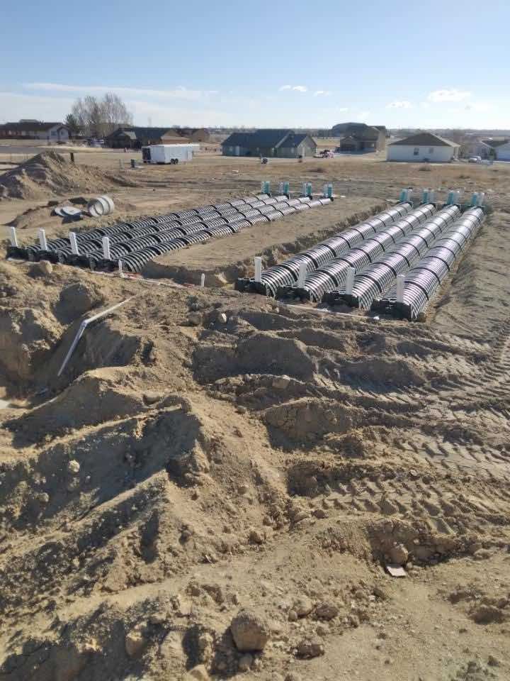 A construction site with a lot of dirt and a lot of pipes in the dirt.