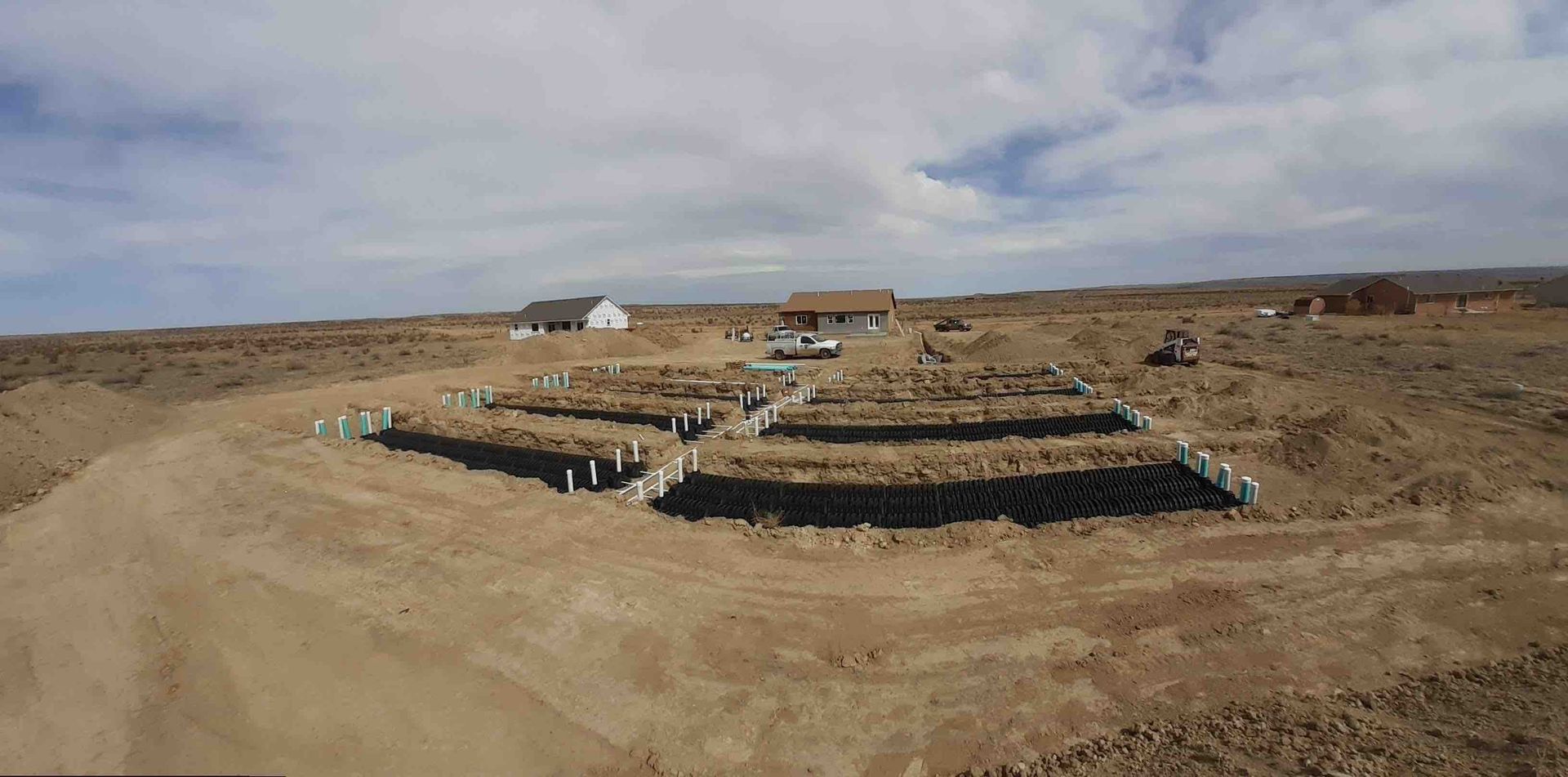 An aerial view of a dirt field with a house in the background.